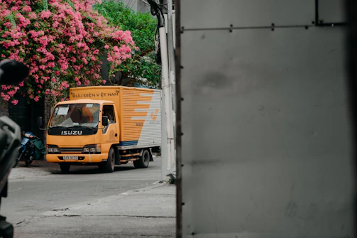 yellow and white truck parked beside white wall
