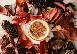 white ceramic mug with coffee on red leaves