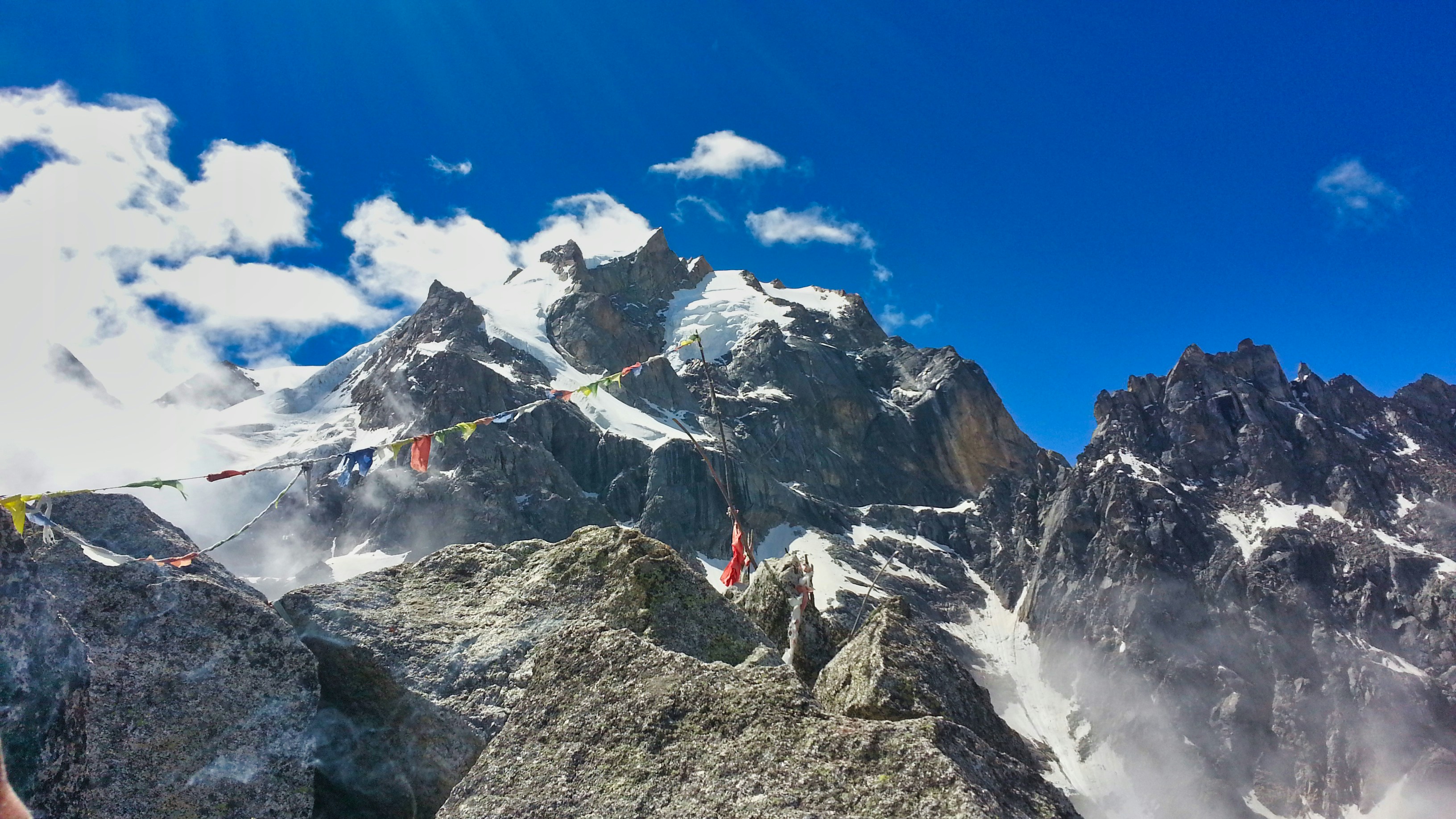 Colorful Tibetan prayer flags strung across a mountain pass with blue sky