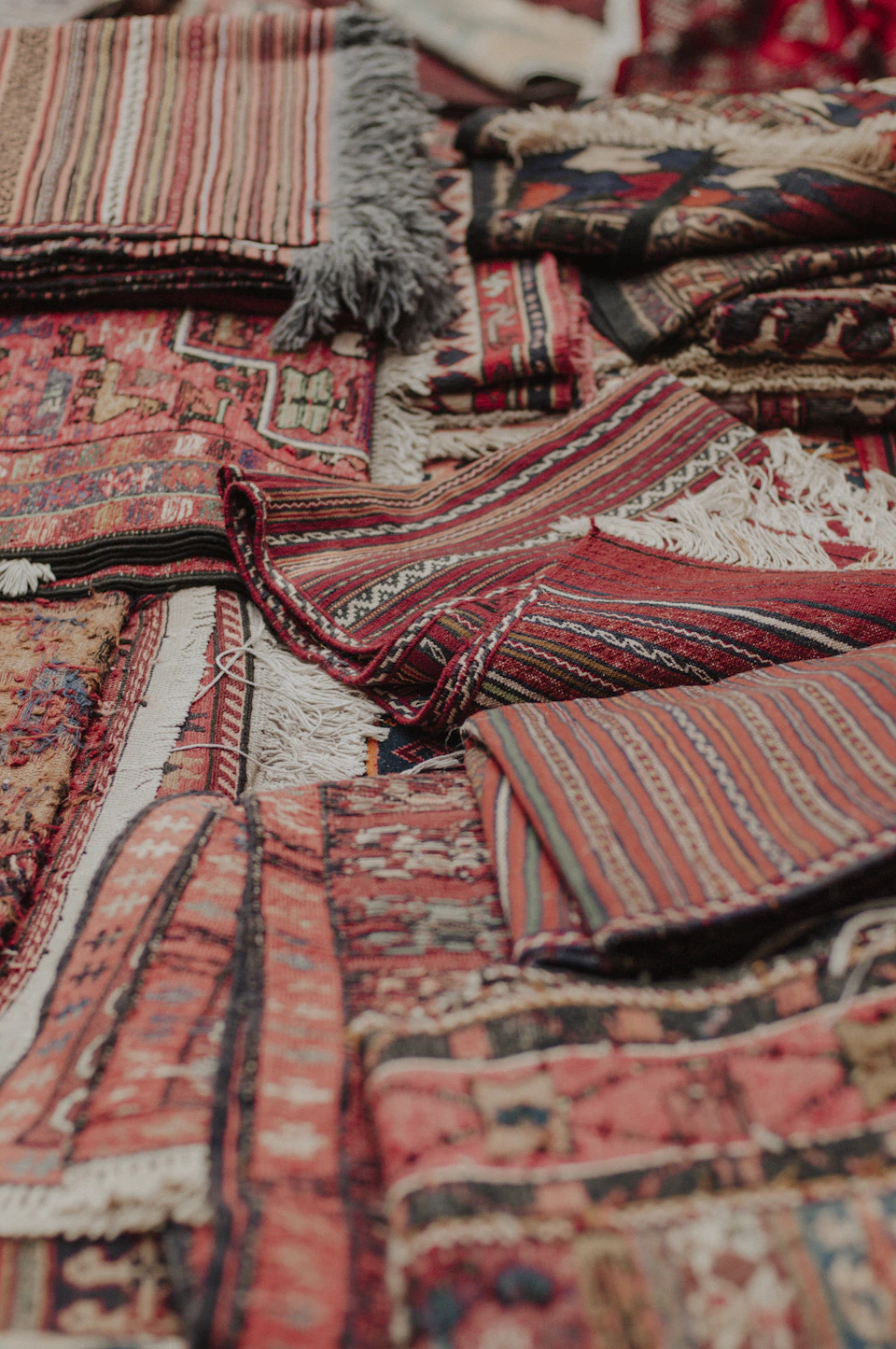 Vibrant colored rugs arranged in various patterns on a table with blurred background