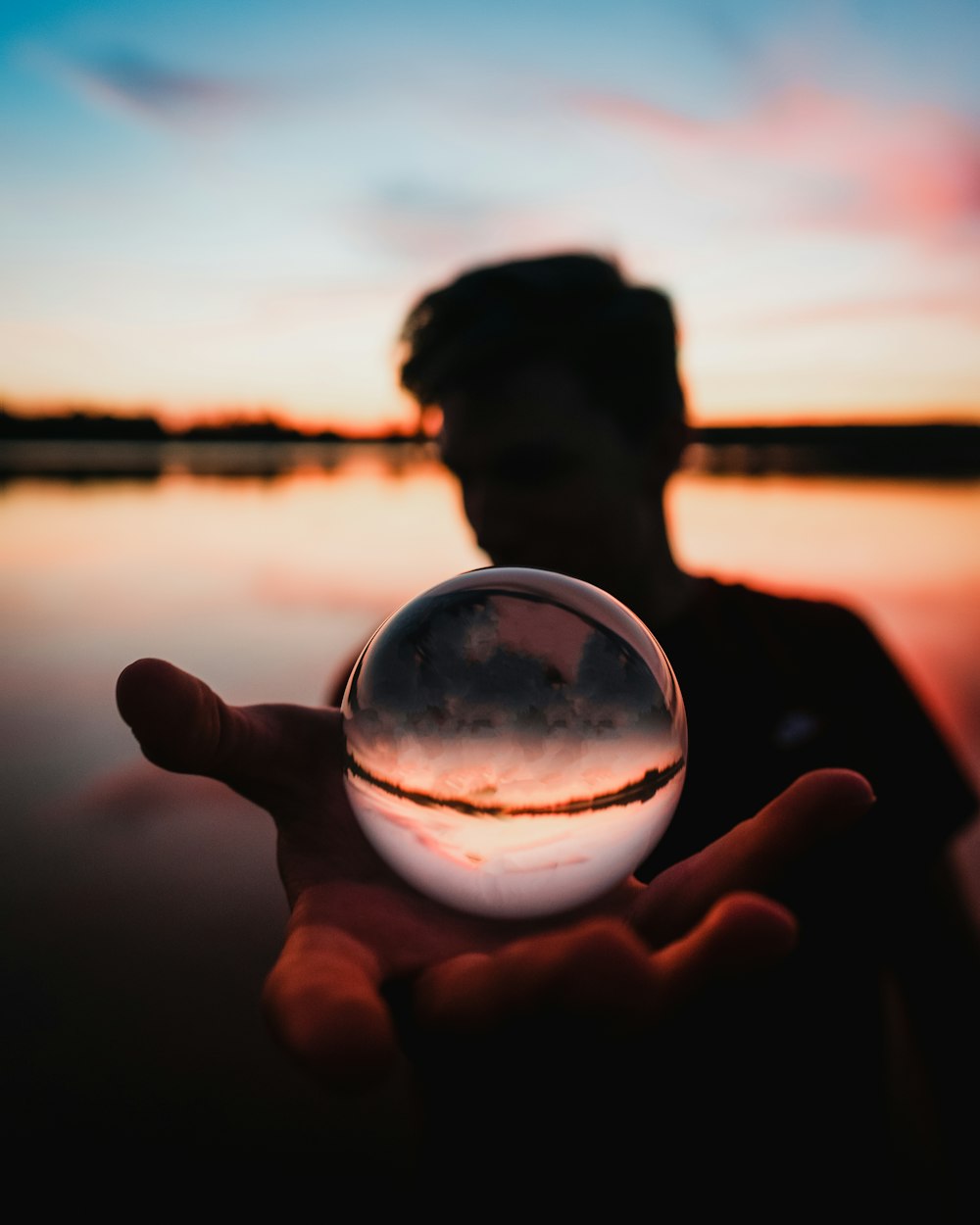 Persona sosteniendo una bola de vidrio transparente