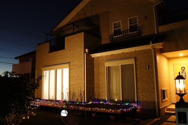 Evening shot of a completed aanbouw with warm interior lights glowing through blue-trimmed windows.