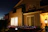 A cozy, freshly painted home exterior glowing warmly under evening lights with a subtle Empire Custom Paint logo overlay.