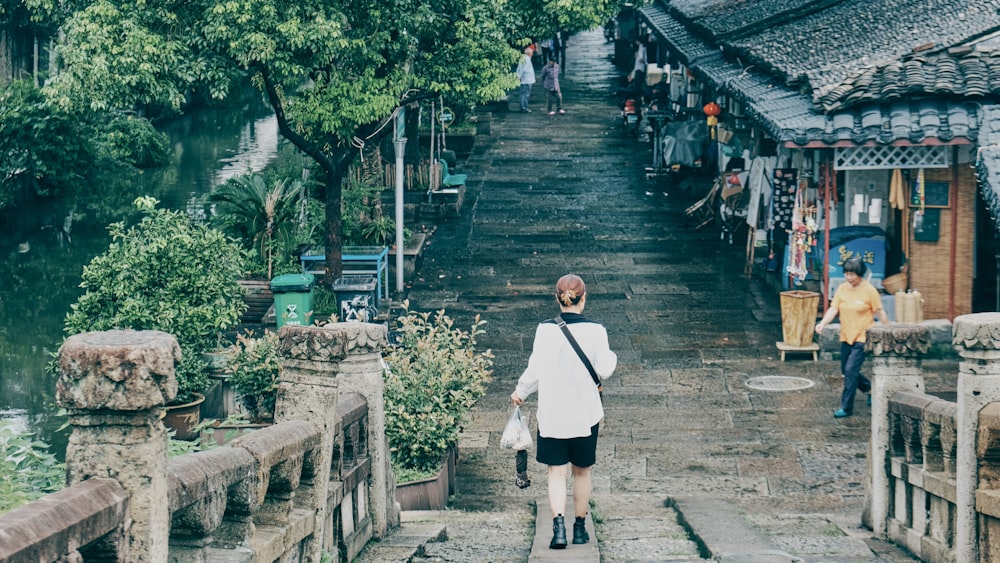 woman in white shirt and black skirt walking on gray concrete stairs