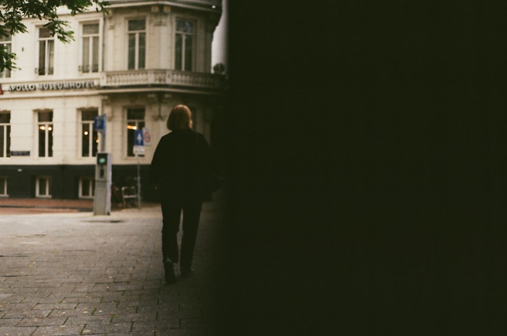 man in black suit walking on sidewalk during night time