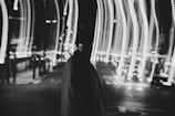 grayscale photo of person in black hoodie walking on street