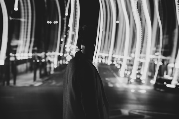 grayscale photo of person in black hoodie walking on street