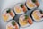 Several pieces of sushi rolls arranged on a white plate. The rolls contain ingredients like crab sticks, shredded egg omelet, carrot, and leafy greens wrapped in rice and seaweed.