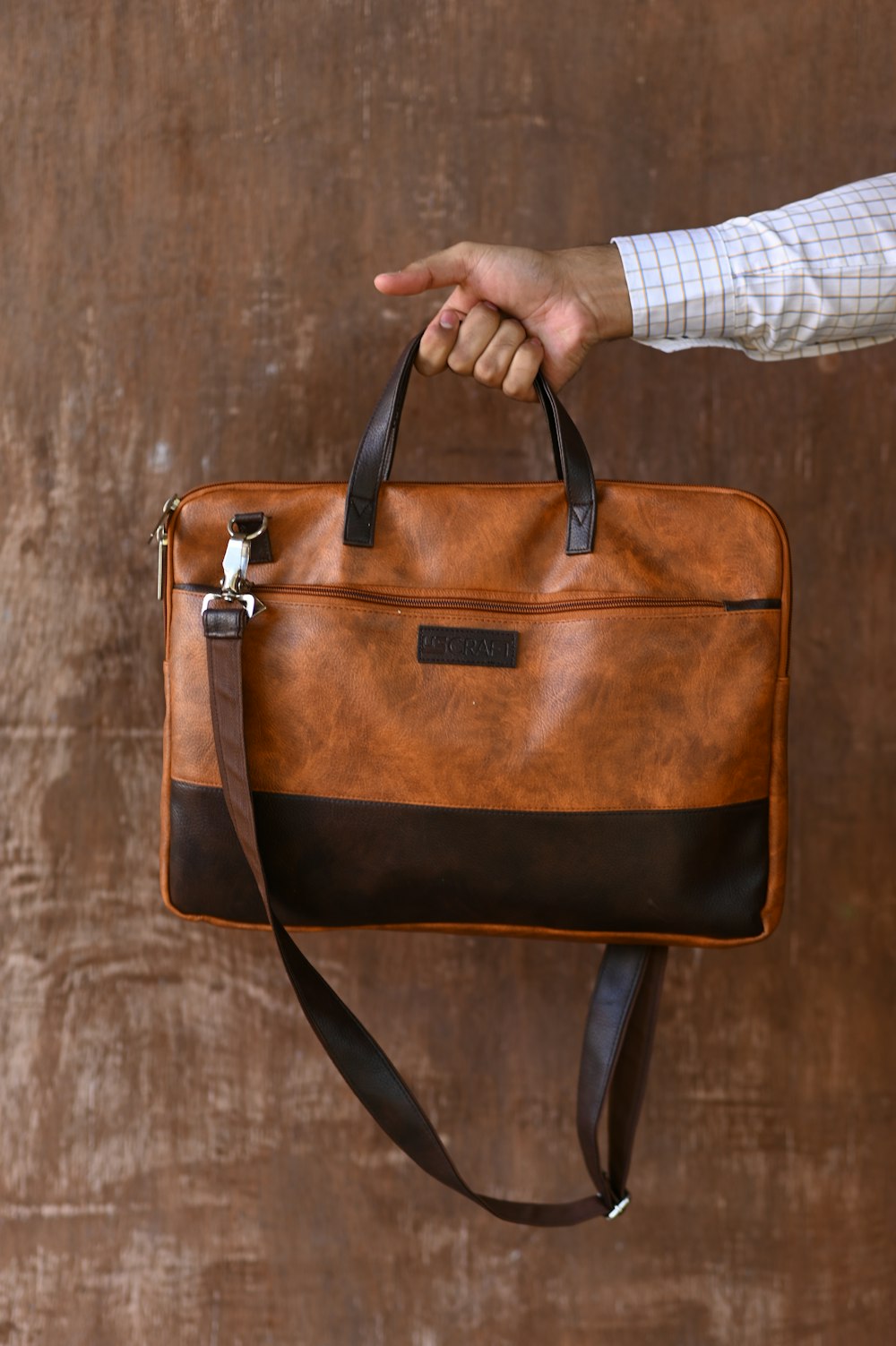 person holding brown leather sling bag
