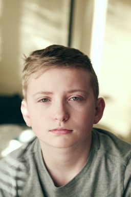 fair hair boy in gray crew neck shirt looking into the camera