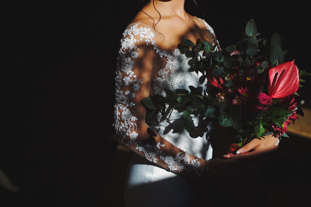 woman in white floral dress holding red rose bouquet