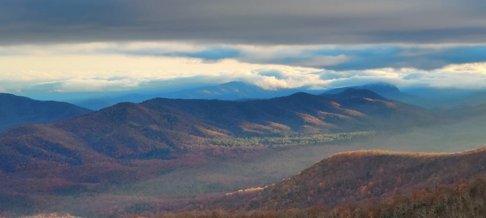 brown and green mountains under white clouds during daytime