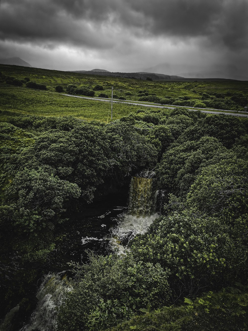 green trees on mountain under cloudy sky during daytime