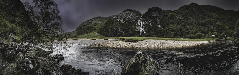 water falls on green grass field near green mountain during daytime