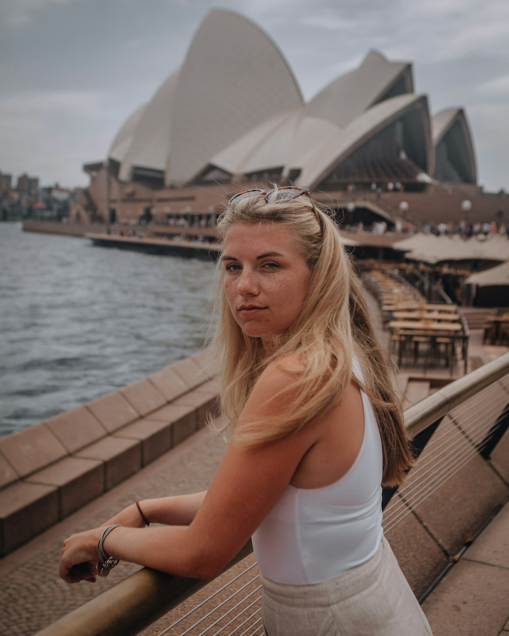 woman in white tank top sitting on brown wooden dock during daytime