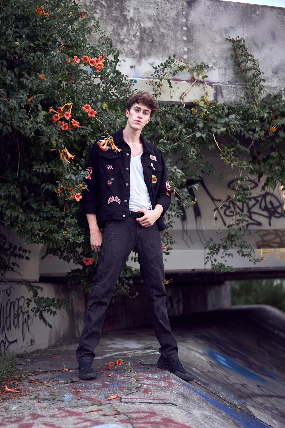 man in black jacket and black pants standing beside green plant