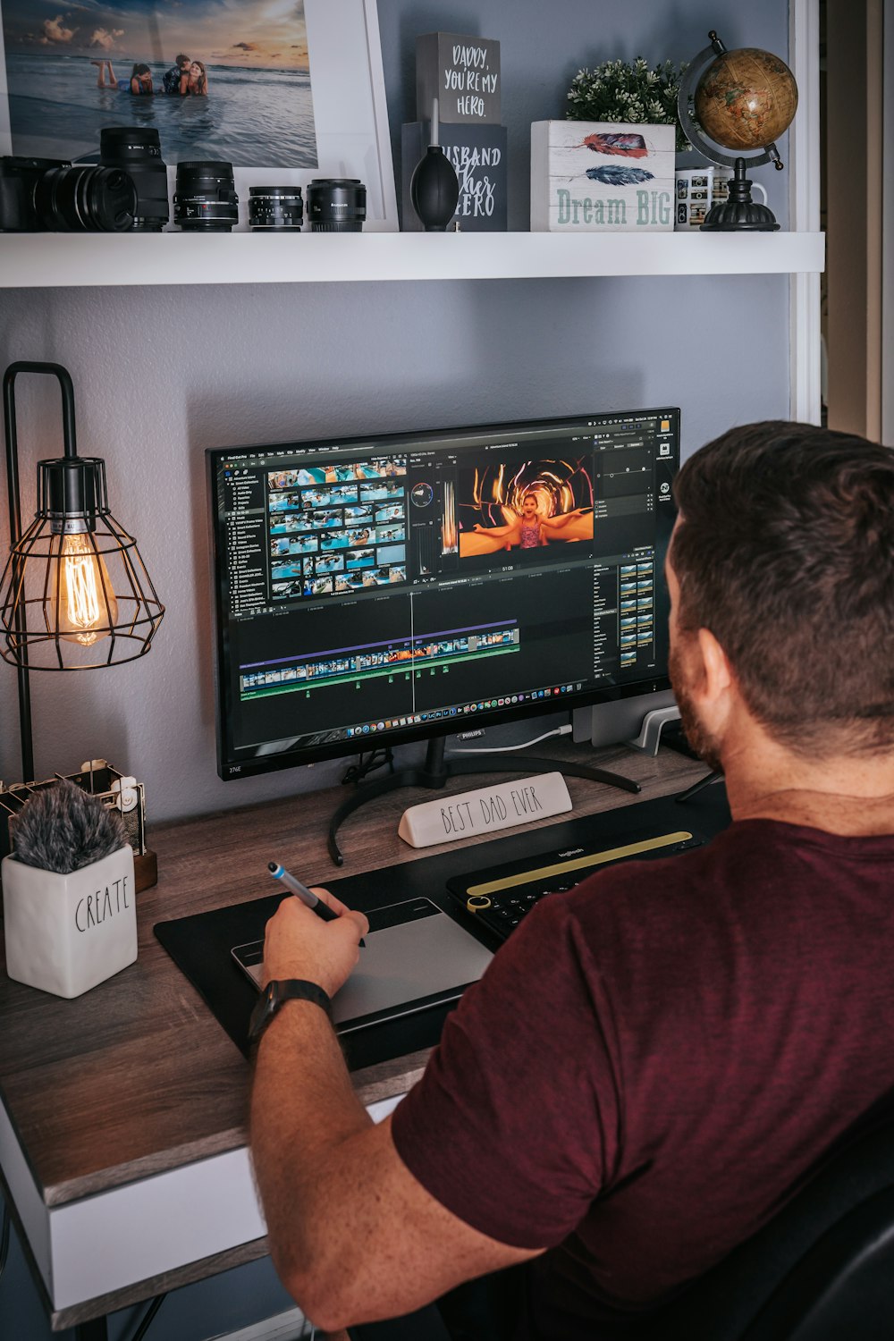 man in red shirt sitting in front of black flat screen computer monitor