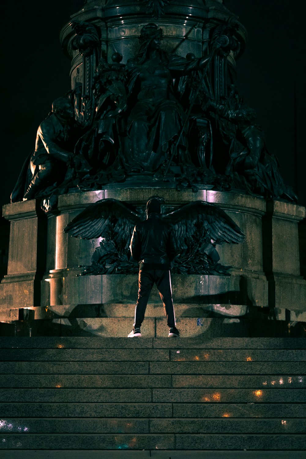 man in black jacket and pants standing beside black statue