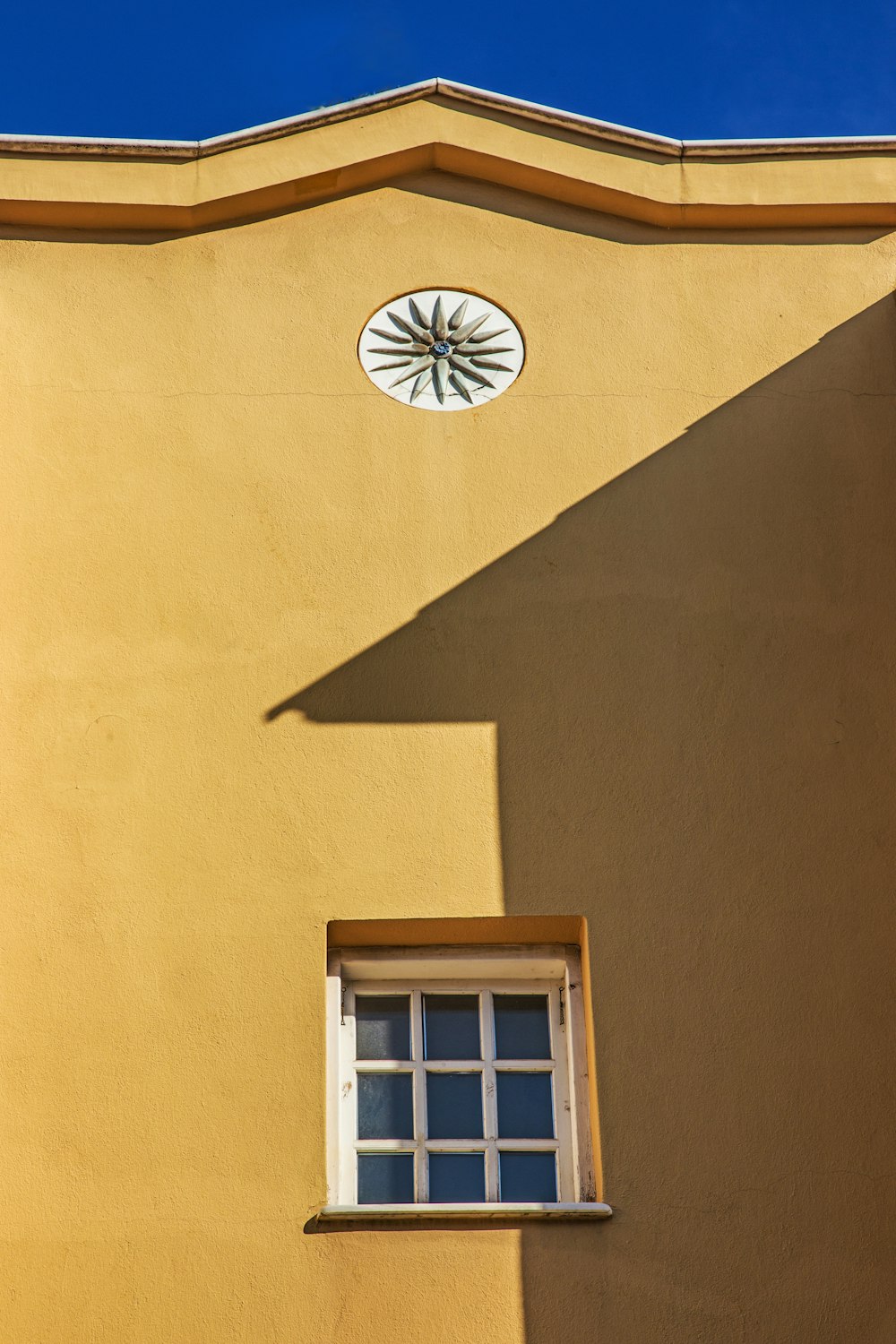 a yellow building with a window and a clock