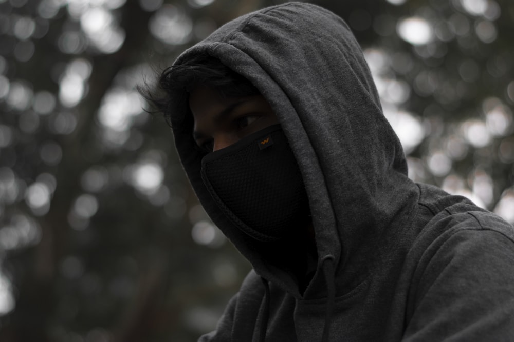 person in gray hoodie wearing black mask