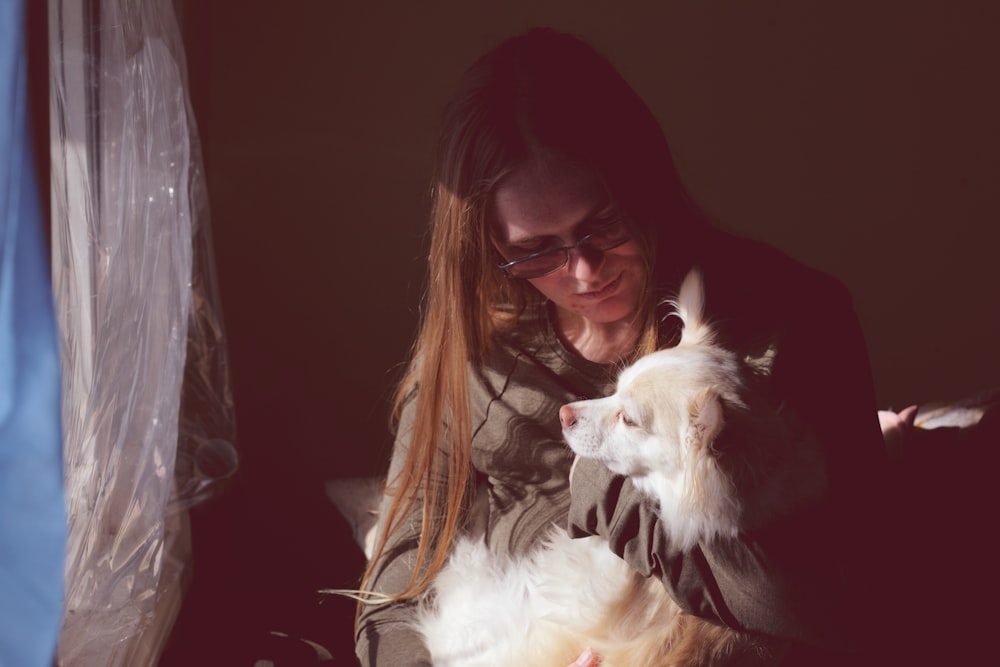 woman in black framed eyeglasses kissing white short coated dog