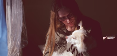 woman in black framed eyeglasses kissing white short coated dog