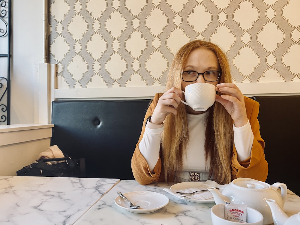 woman in yellow long sleeve shirt holding white ceramic mug