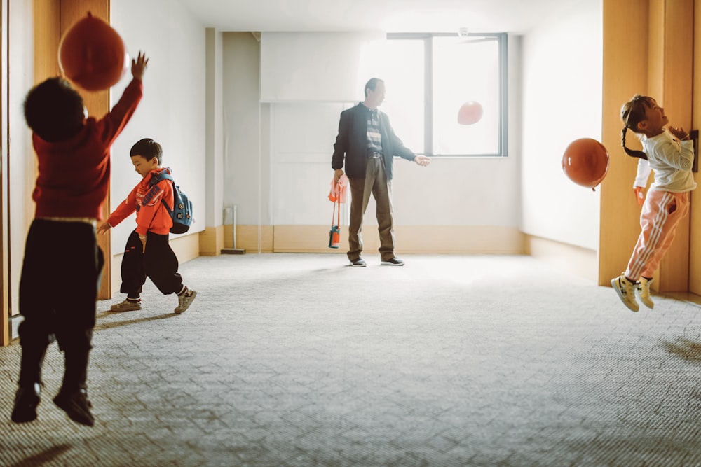 man in black jacket and black pants holding boy in orange shirt