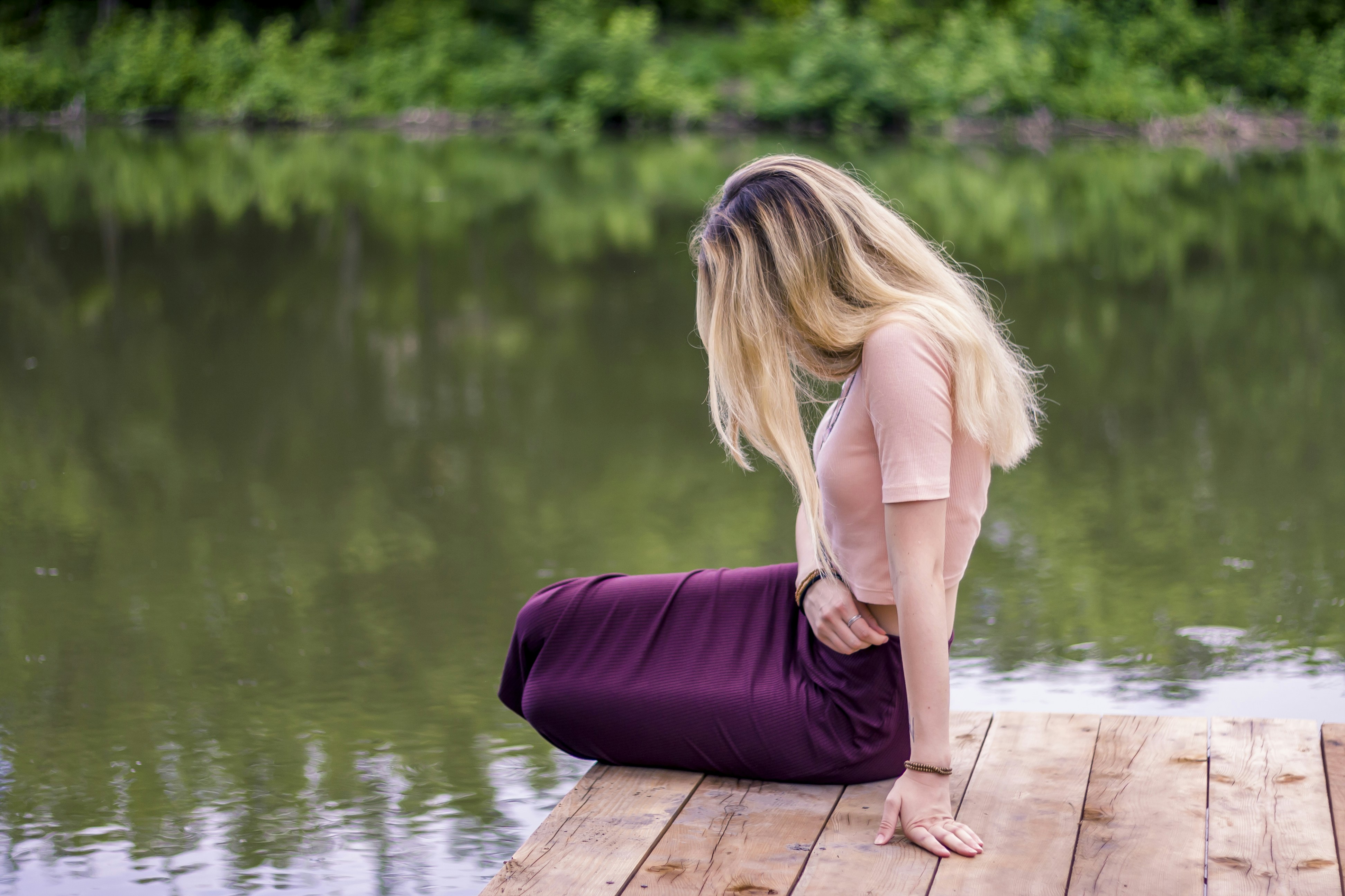 woman in purple dress sitting on wooden dock