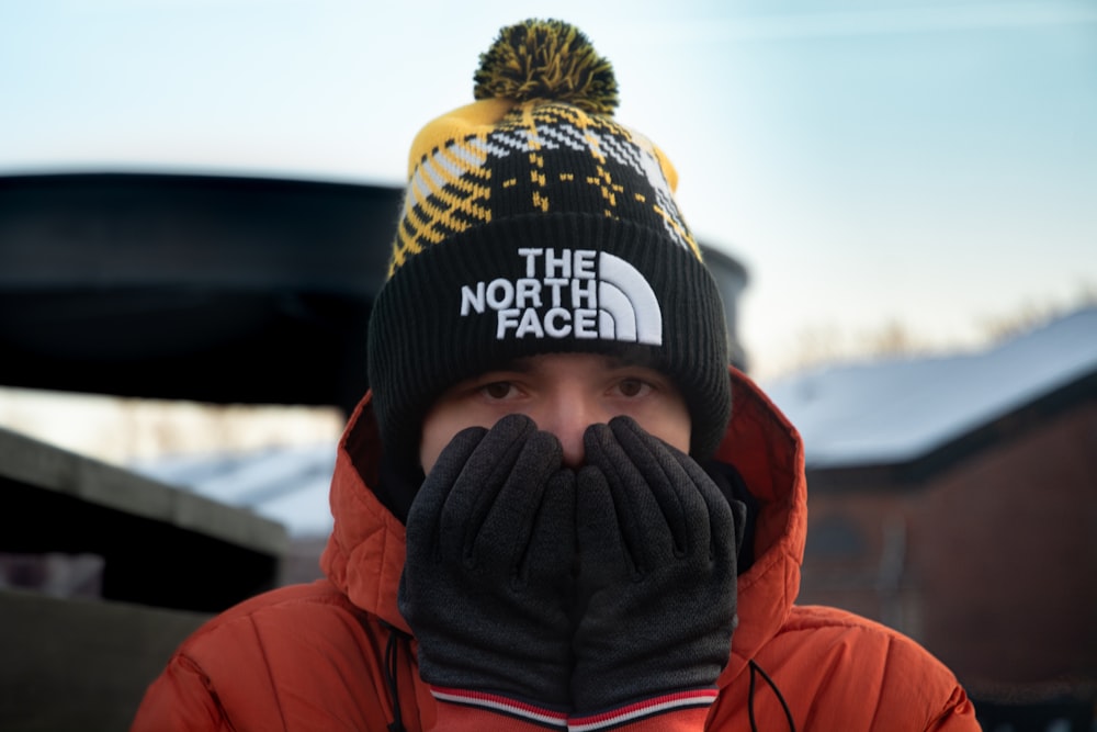 person in red hoodie wearing black and yellow knit cap