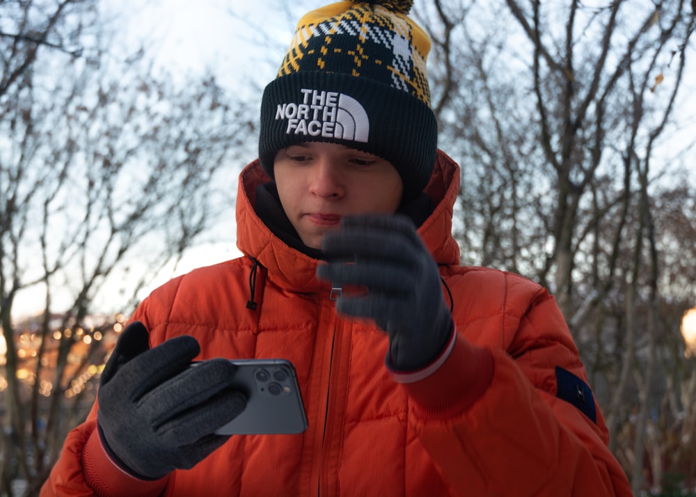 boy in orange jacket holding iphone