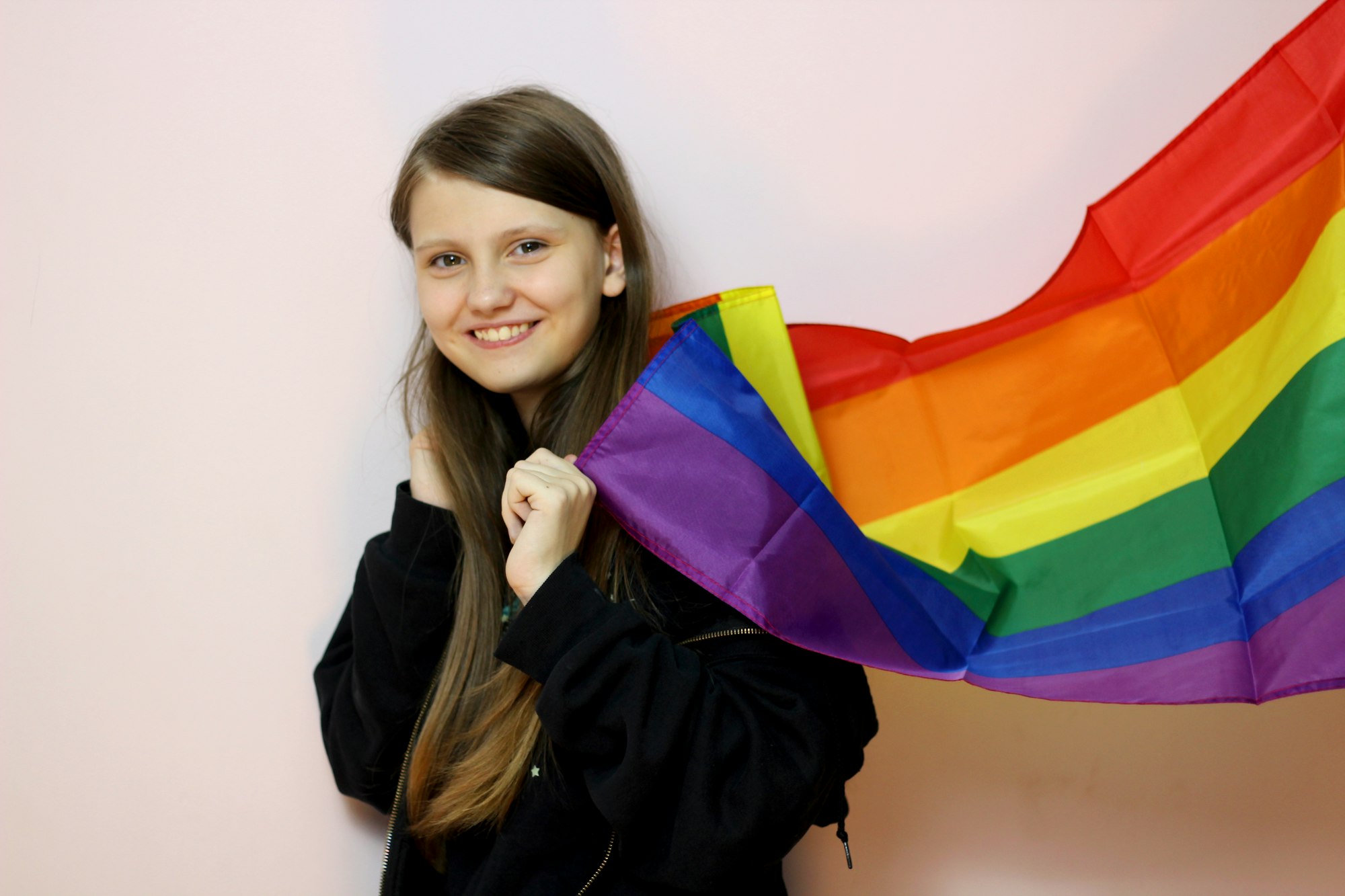 A teenager holding a rainbow flag.