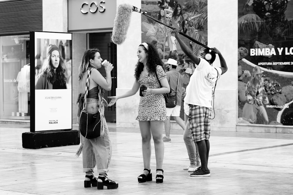 Mujer en vestido sin mangas de lunares en blanco y negro sosteniendo palo blanco y negro