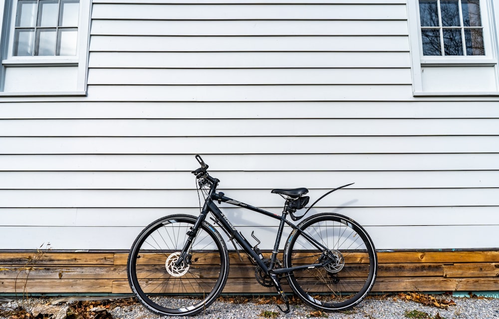 black commuter bike parked beside white wall