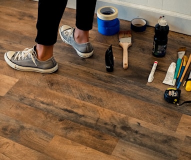 person in black pants and white and black nike sneakers standing on brown wooden floor