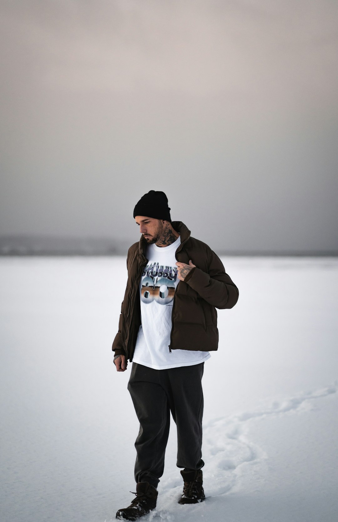 woman in gray jacket and black pants standing on snow covered ground