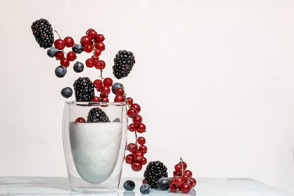 Baies rouges et noires sur tasse en verre transparent