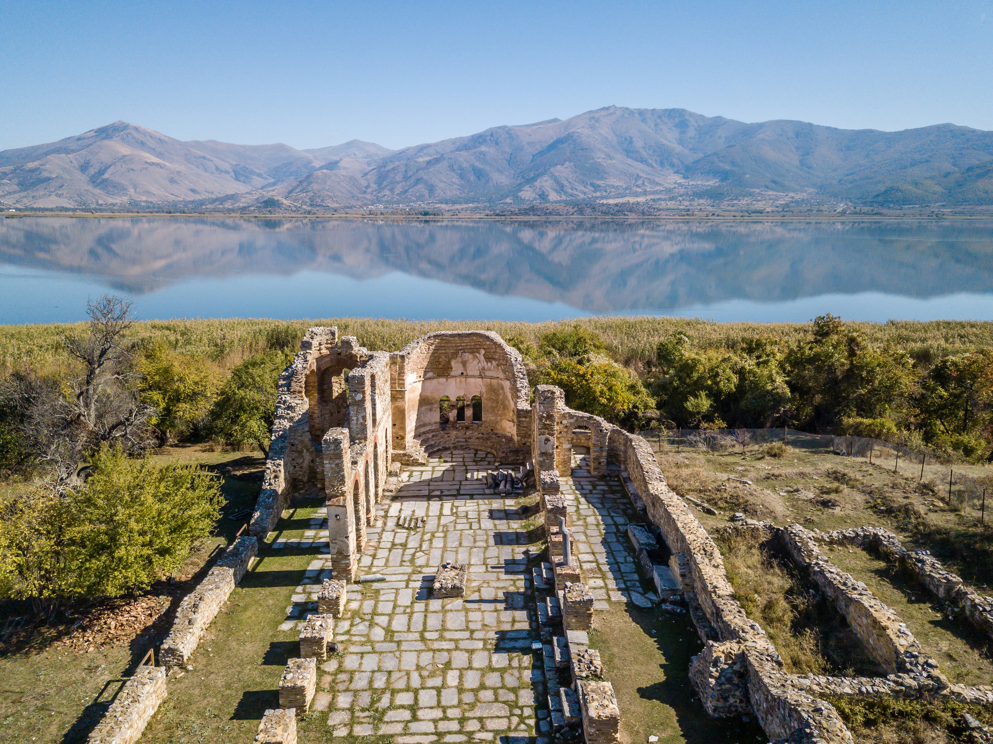 edificio in cemento marrone vicino agli alberi verdi e allo specchio d'acqua durante il giorno