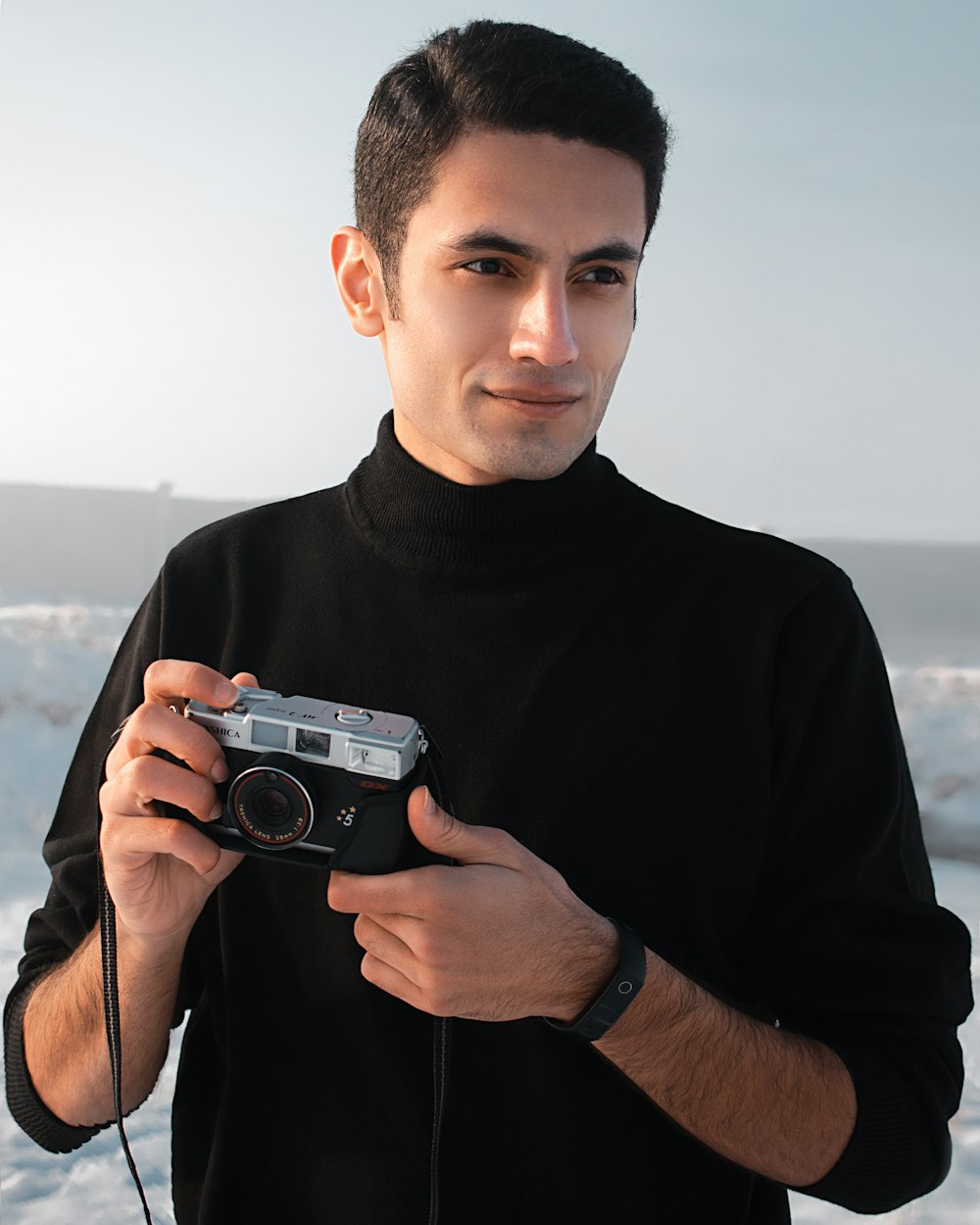 man in black crew neck shirt holding gray camera