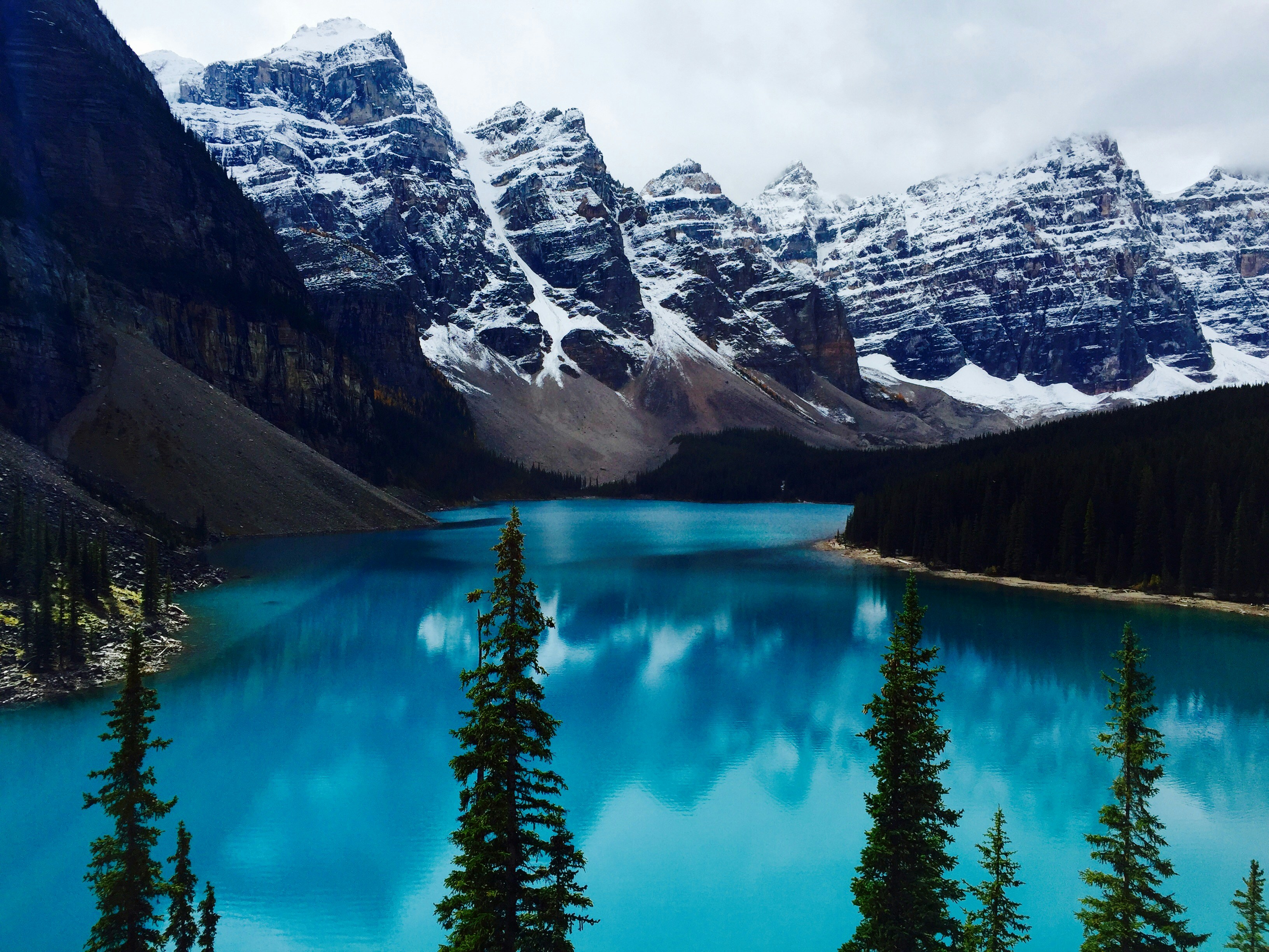 lake surrounded by trees and snow covered mountains