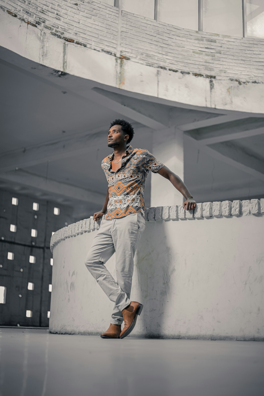 man in white pants and brown shoes standing on gray concrete wall