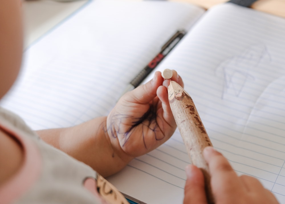 a person holding a pencil and writing on a notebook