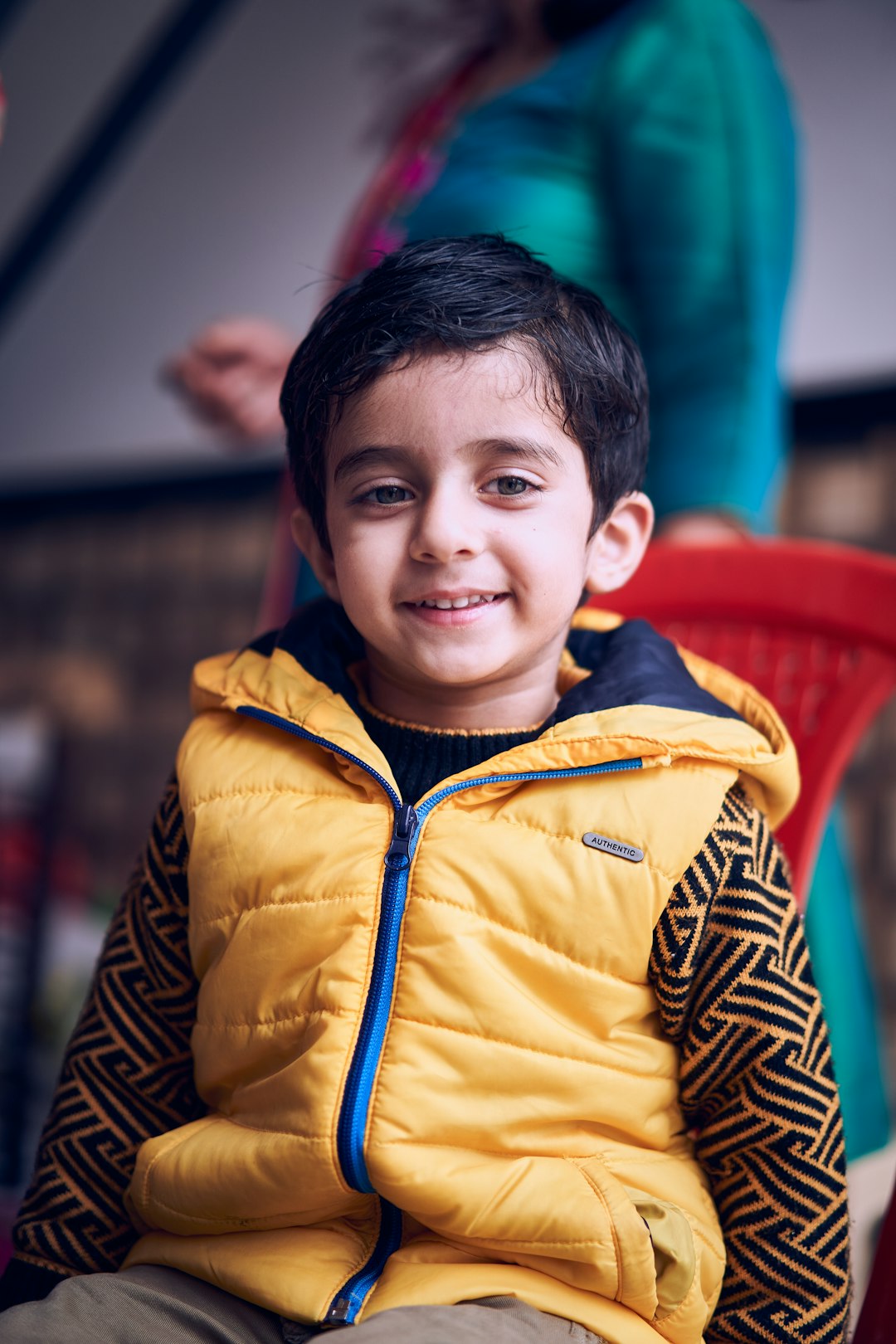 boy in yellow zip up jacket smiling