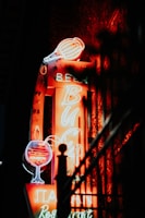 A brightly lit neon sign displaying the words wine, beer, and restaurant. The sign features images of a wine glass and a beer mug in vibrant neon colors, creating a warm and inviting glow in the darkness.