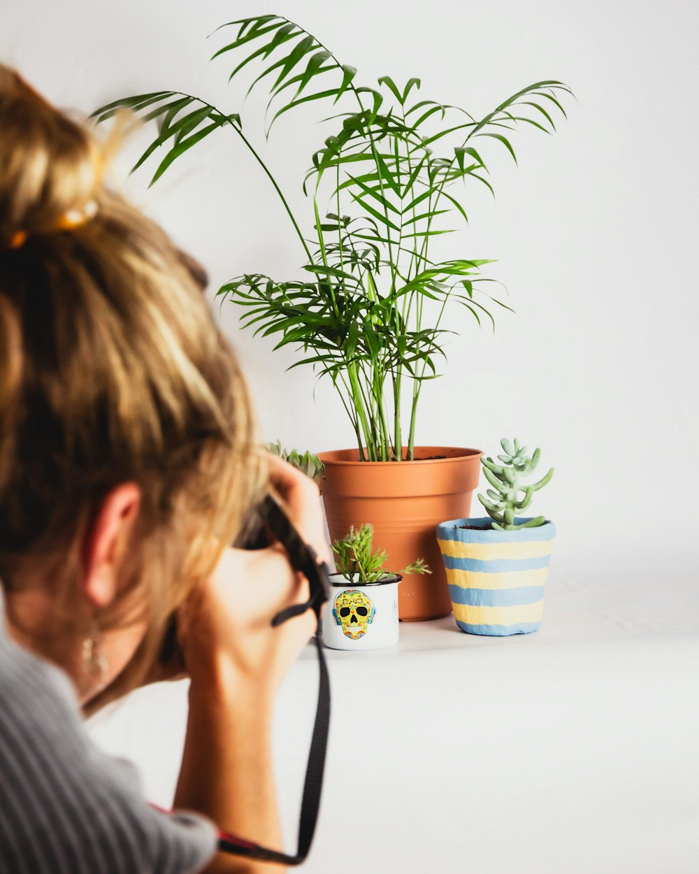 woman in gray shirt holding black ceramic mug with green plant