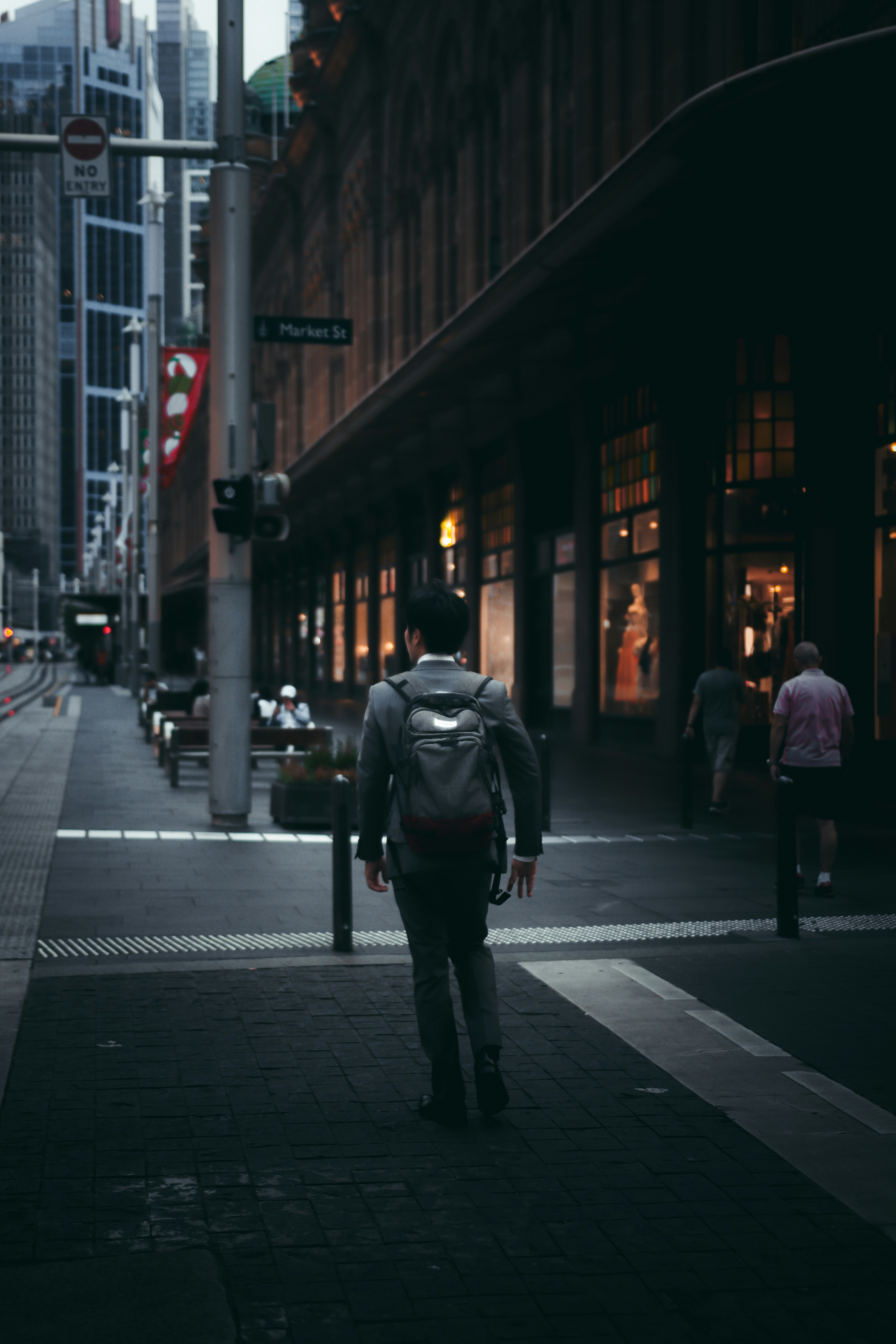 man in black jacket walking on sidewalk during night time