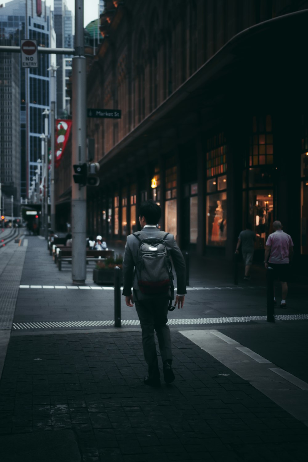 man in black jacket walking on sidewalk during night time