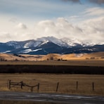 brown field near mountains under white clouds during daytime