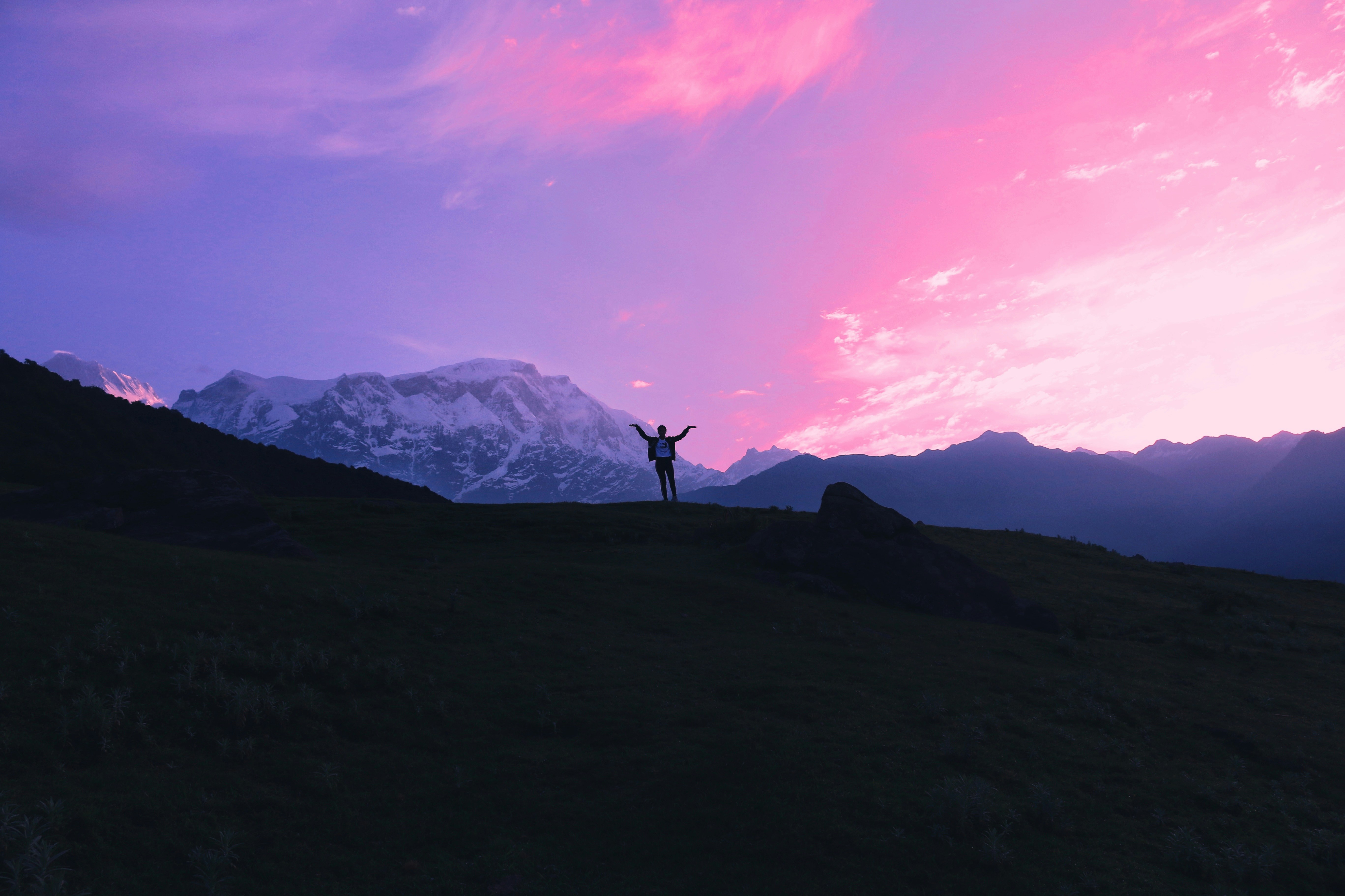 silhouette of person standing on hill during sunset