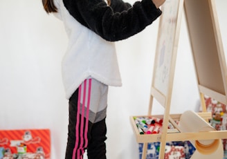 woman in black long sleeve shirt and white and pink skirt holding brown wooden stick